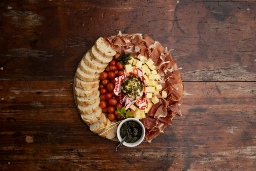 Antipasti-Platte mit Schinken, Käse und Brot auf Holz