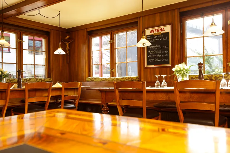 Holzstube mit Fenstern zur Hauptstraße und Tafel an der Wand
